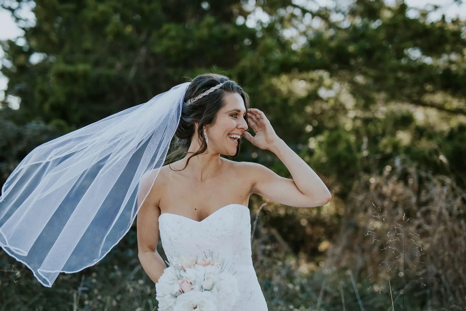 Laughing bride with her veil blowing in the wind