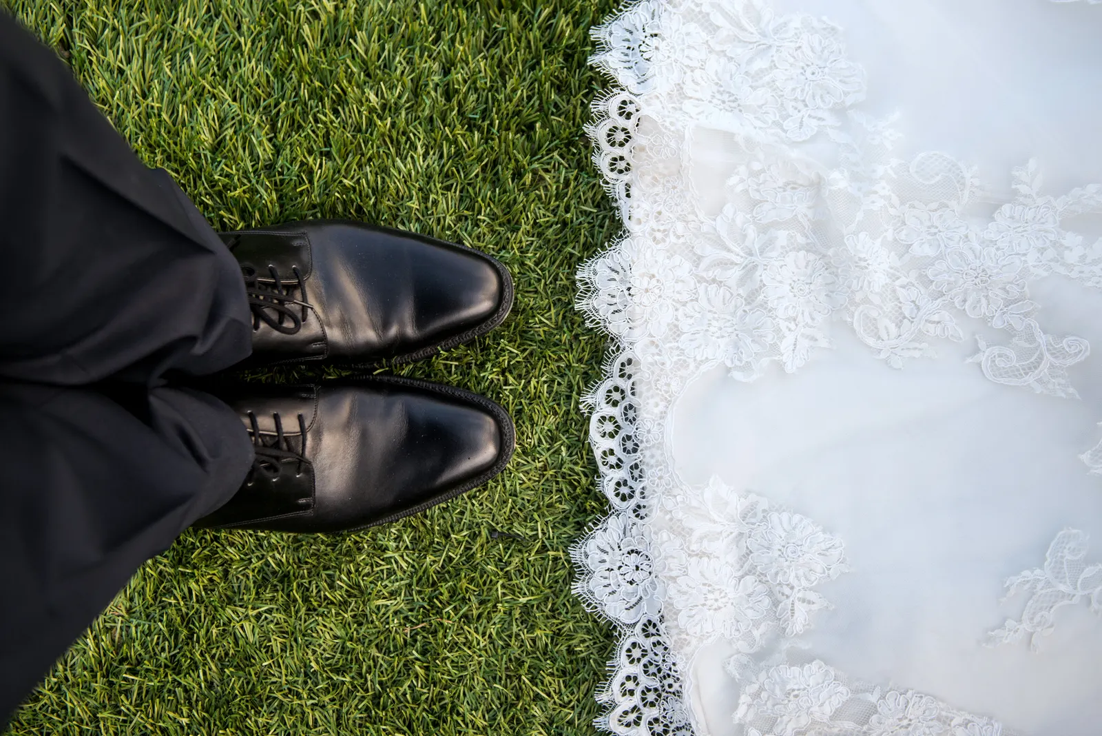 Lace wedding dress and groom shoes on grass